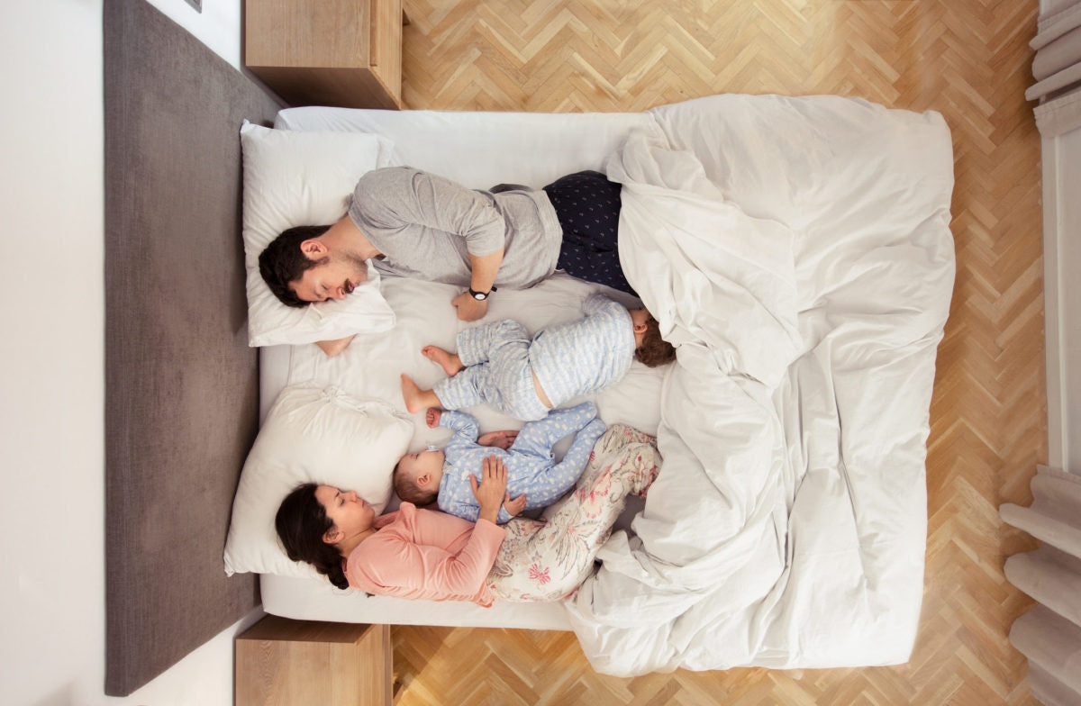 A father and a mother sleeping with thier kids in a room