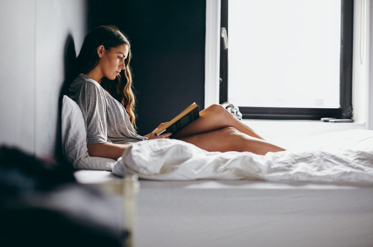 Girl sitting on bed and reading book