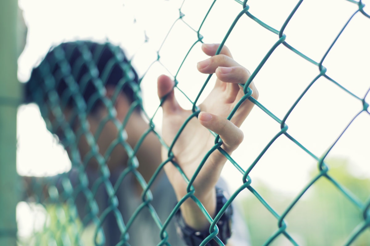 Person standing behind cage with depression