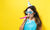 woman with party hat with noisemaker on a yellow background