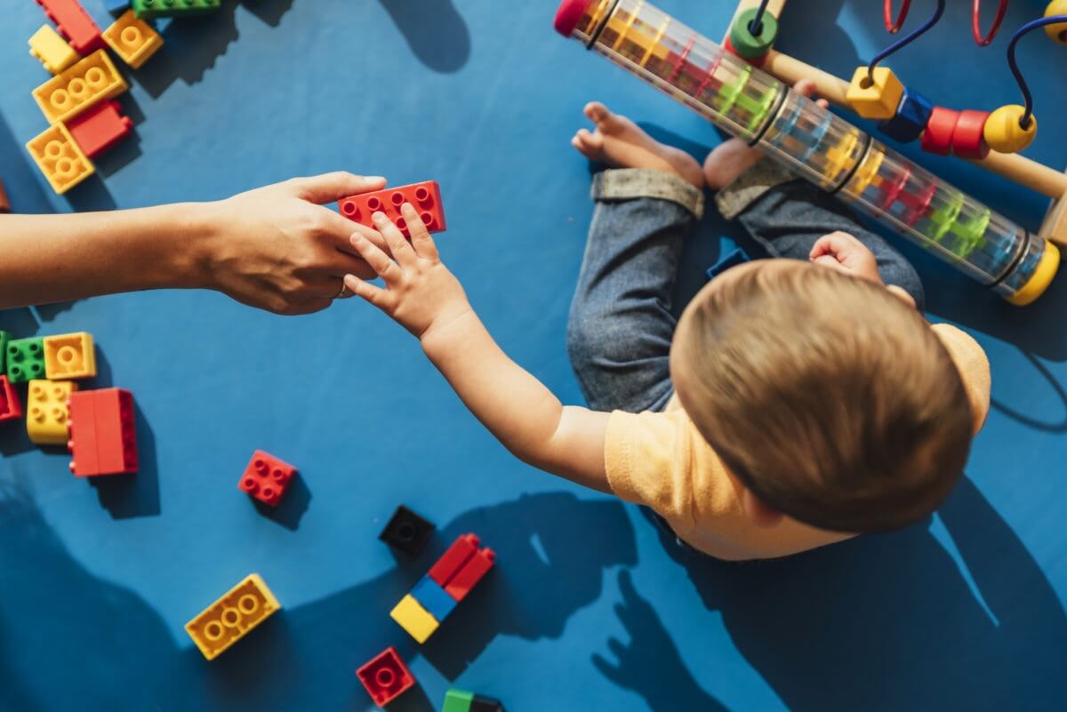 person handing a child a building block