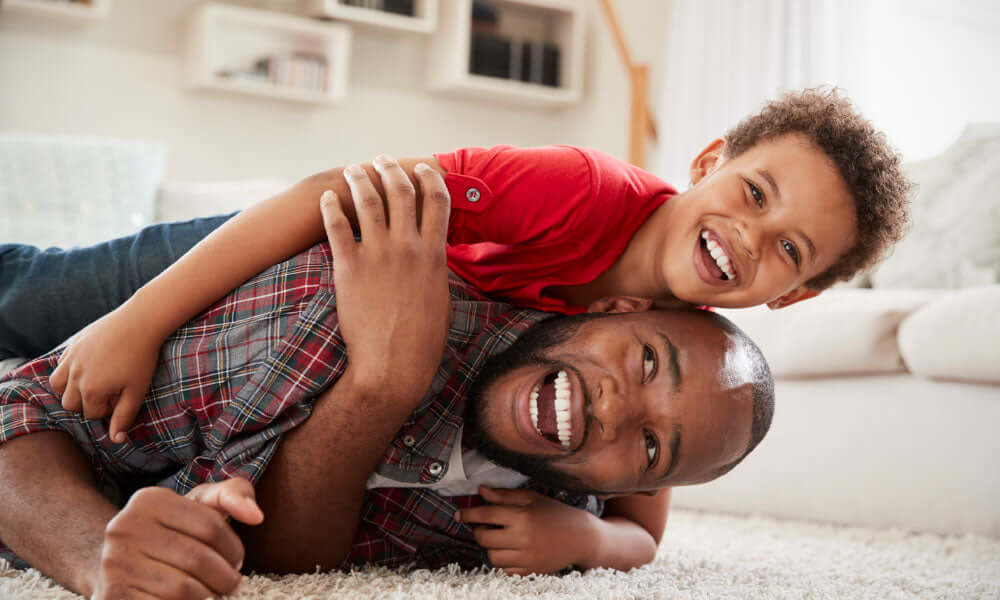 son fils grimpe sur le dos de son père alors qu'ils jouent à un jeu