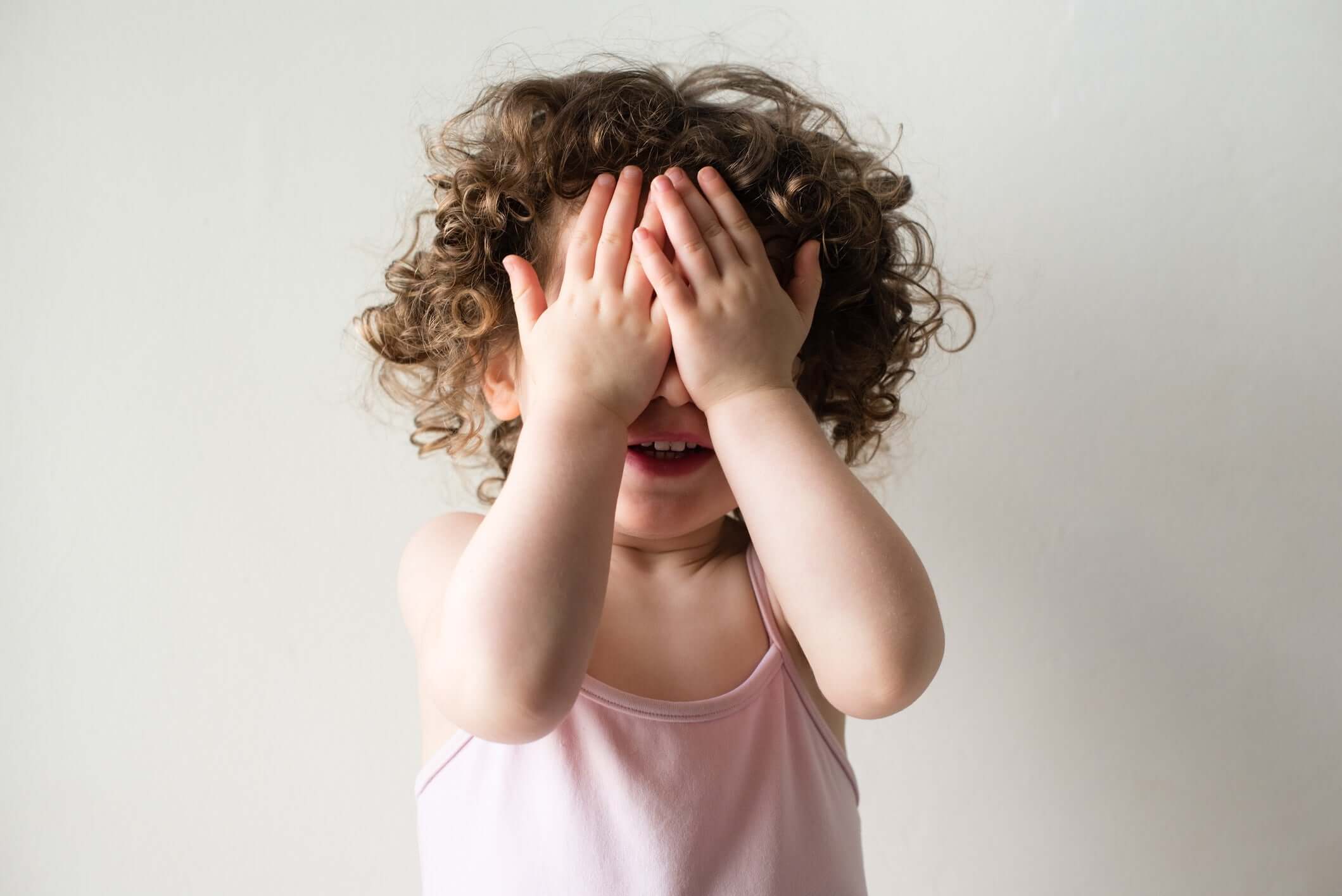 A baby girl closing eyes using hand