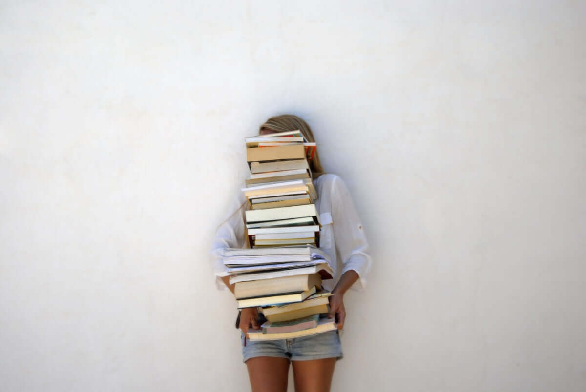 A girl is holding books by covering her face