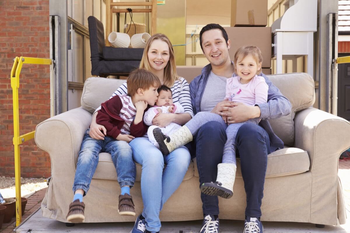 Happy family with kids seated on couch posing for camera