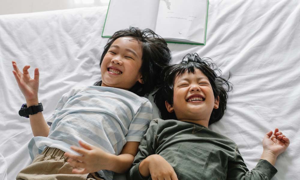 boy and girl laughing in bed