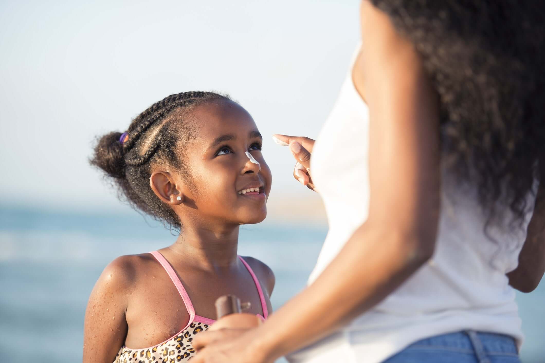 Mother applying moisturizer on daughters nose