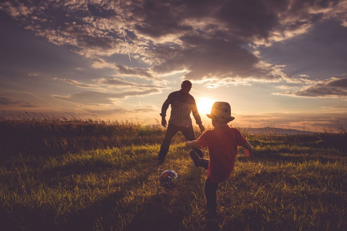 Father and child on a grassland at evening