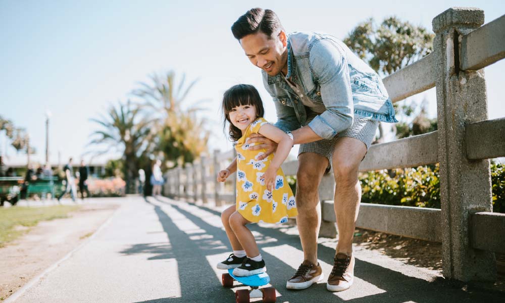 dad teaching daughter how to skateboard