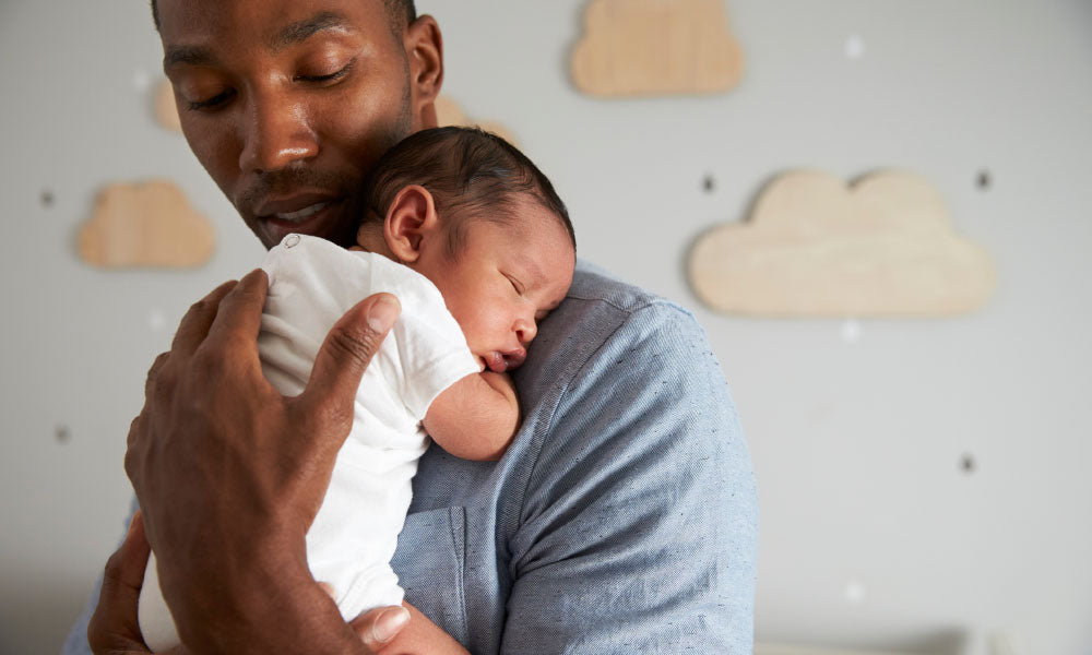 father holding newborn baby son in nursery 