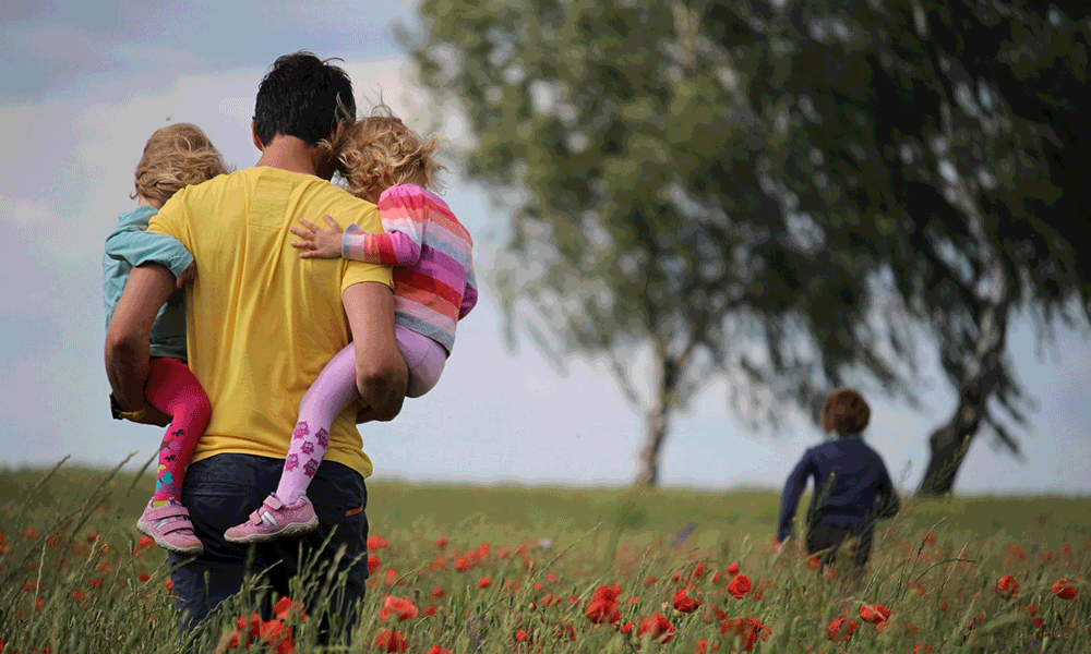 father in field with kids