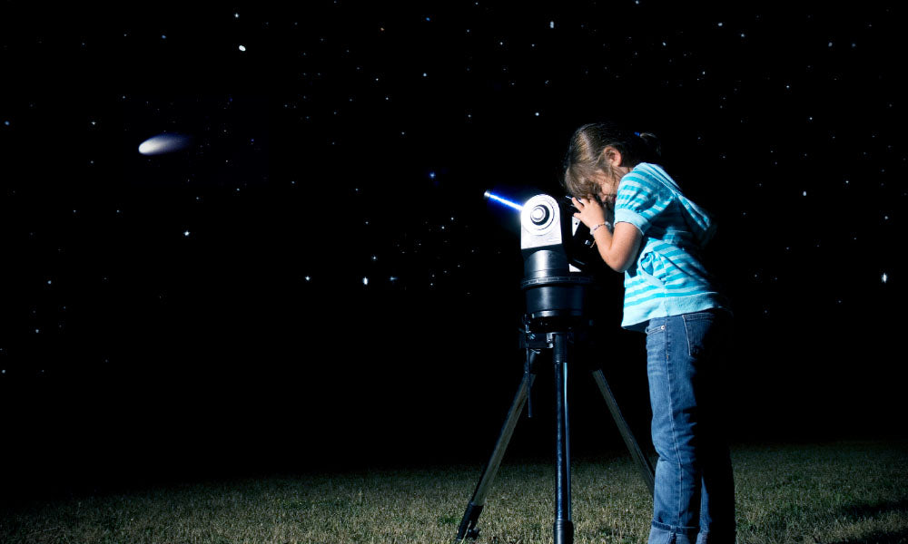 girl looking through telescope