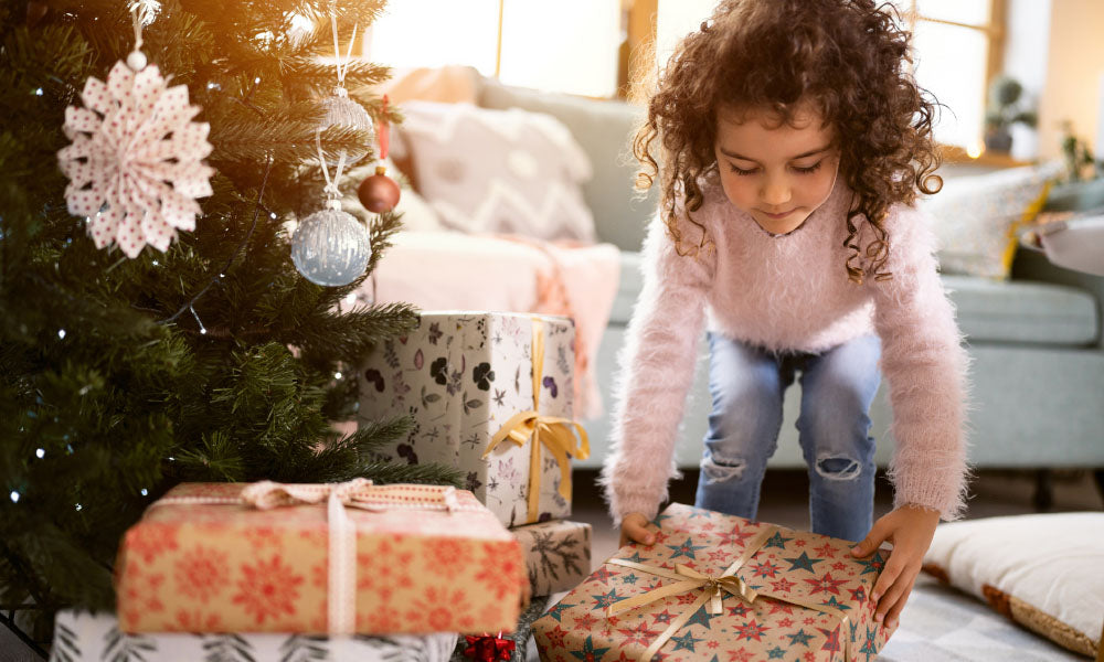 girl placing christmas presents under the christmas tree
