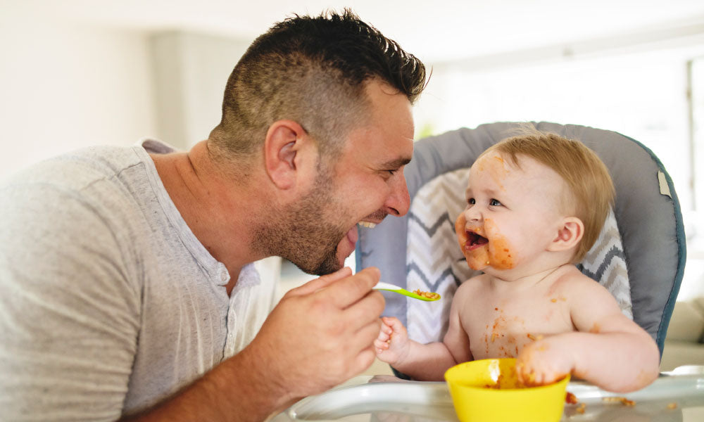 toddler eating food with father