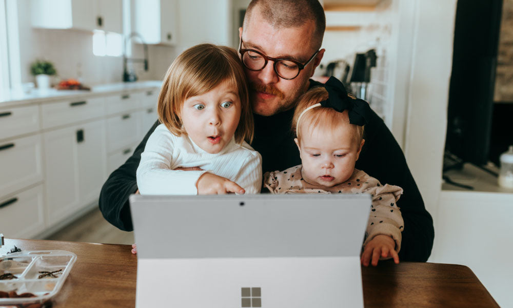 man and two kids looking at computer screen