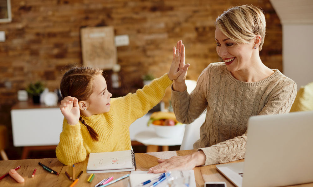 mother and daughter giving high-five during homeschooling