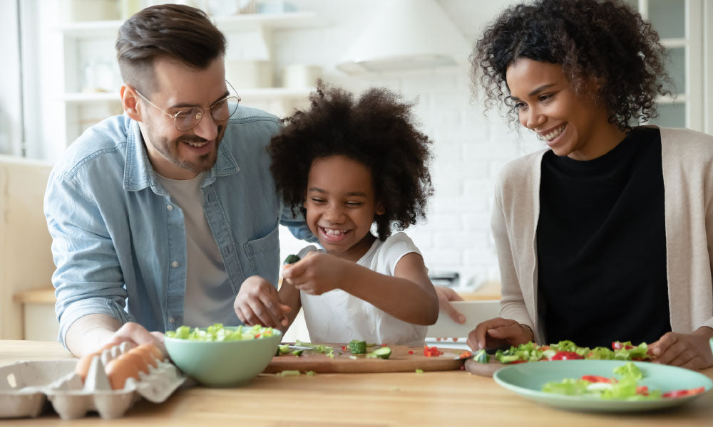 parents with little daughter cooking salad