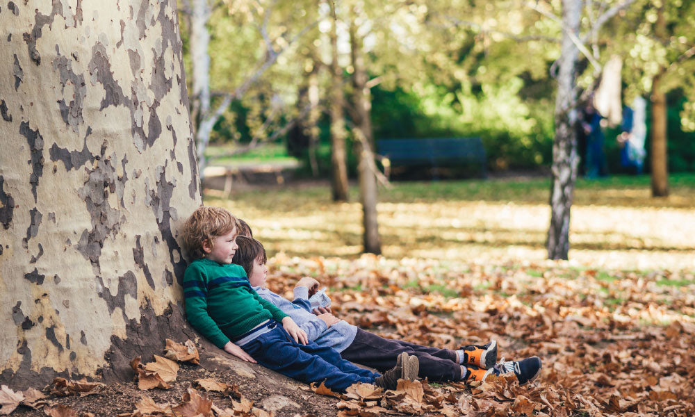 two boys sitting by a tree