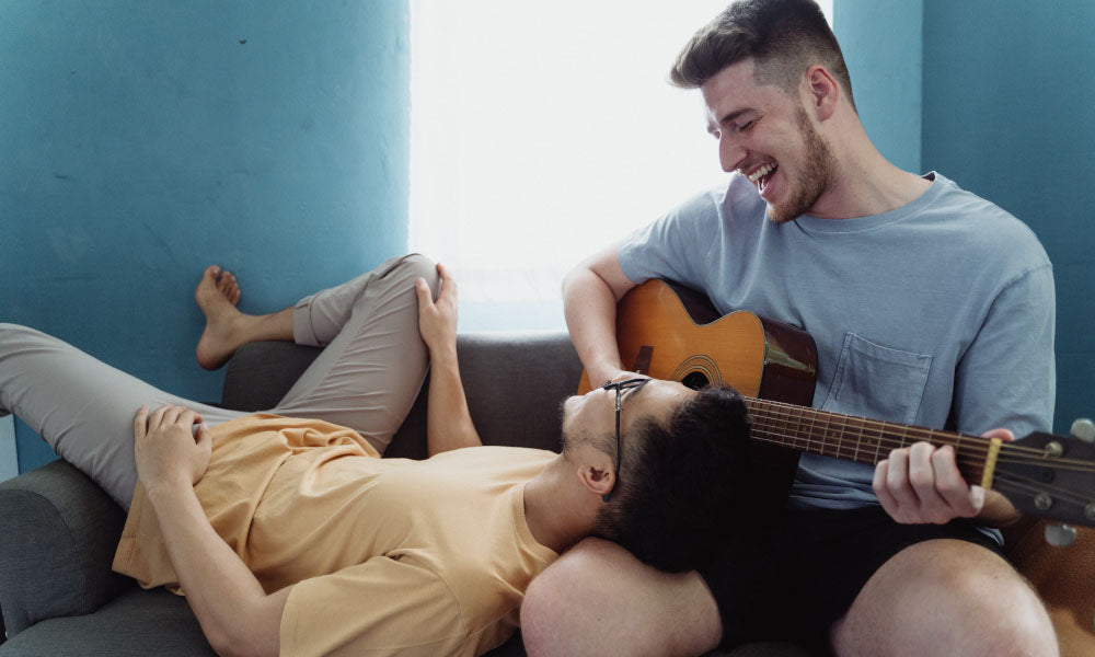 two men laughing with a guitar