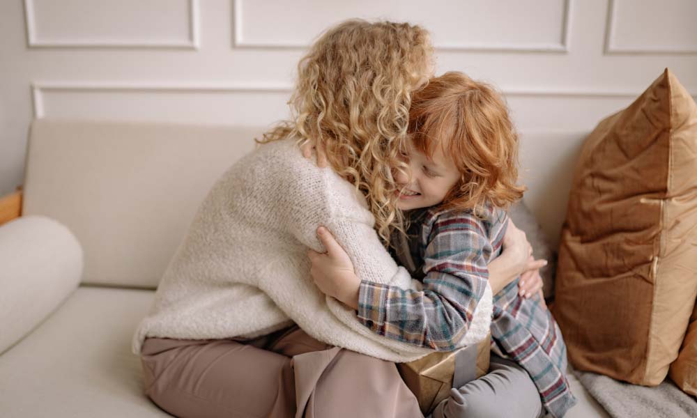 woman and child hugging on a couch