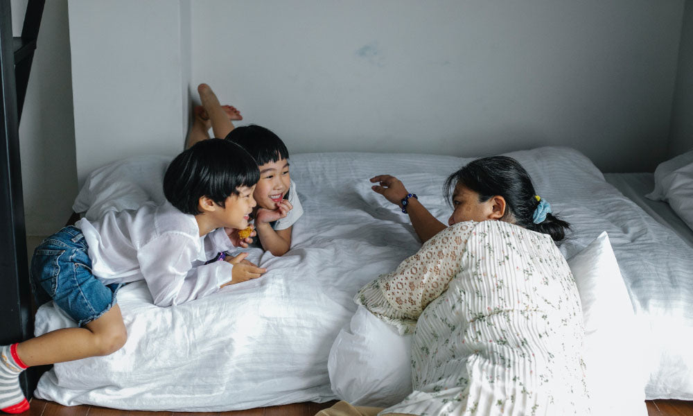 women laughing with two kids in bed