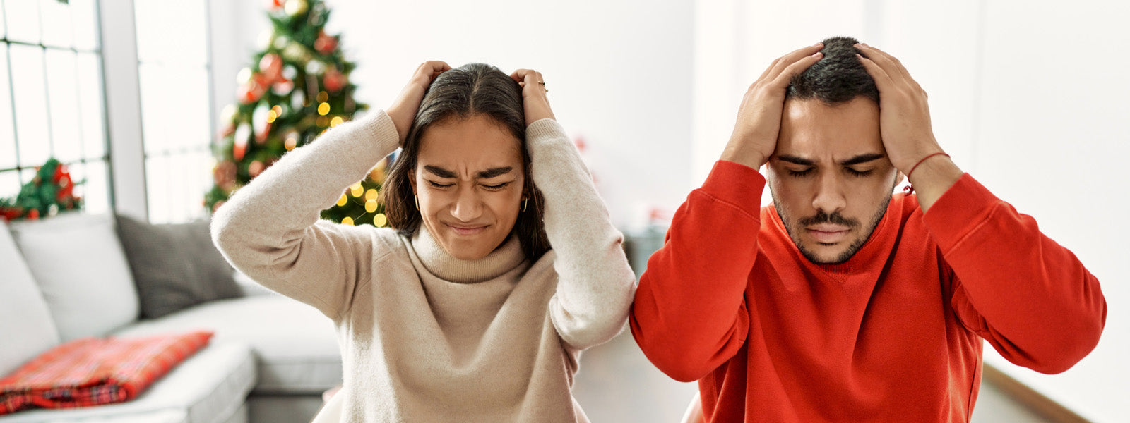 couple sitting on the table by christmas tree suffering from headache