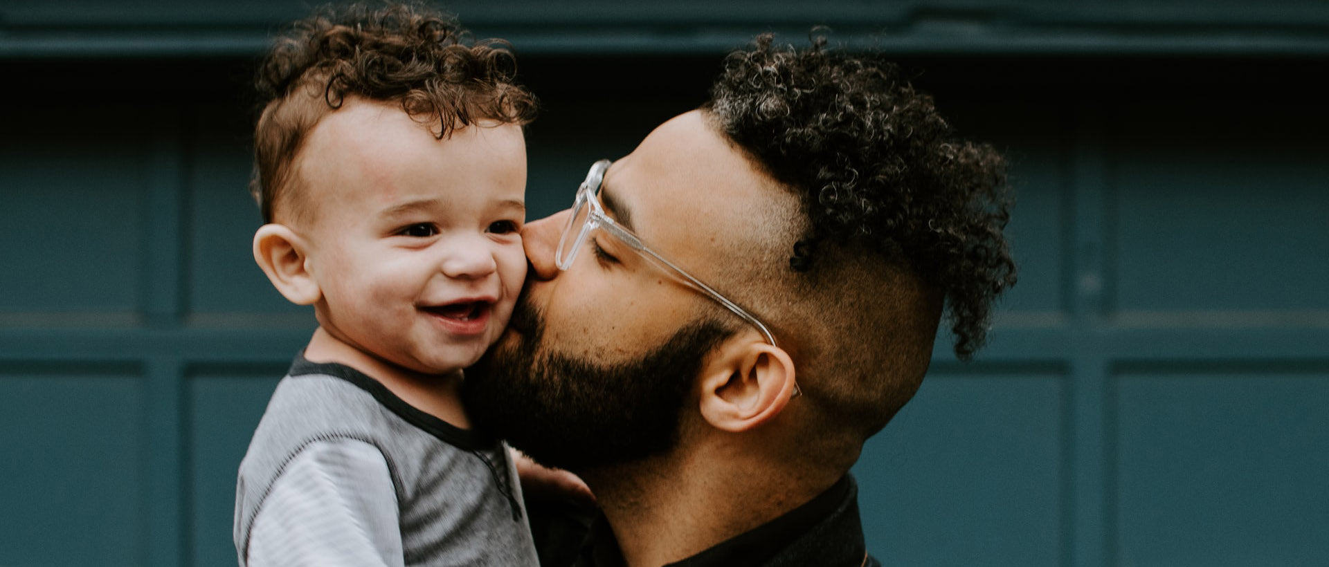 man carrying baby boy and kissing on cheek photo