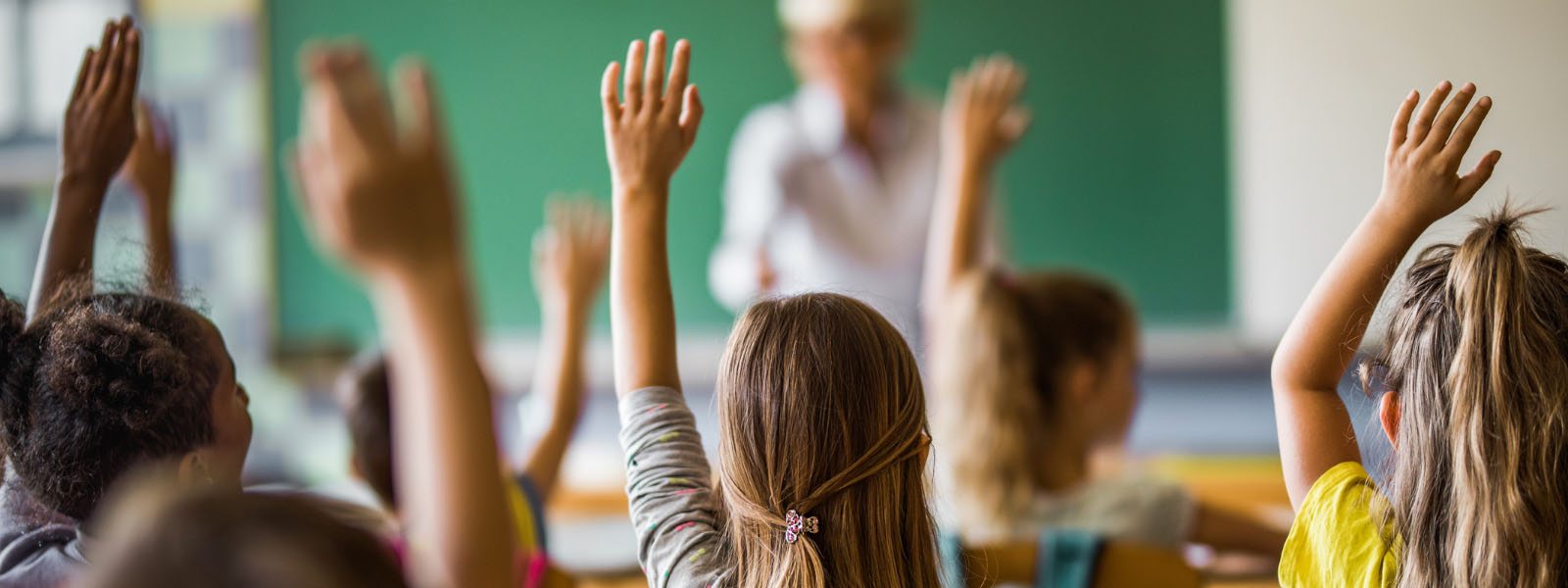elementary students raising their arms on a class