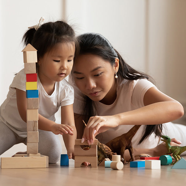 mother and child playing on floor with blocks